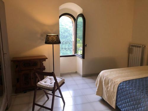 sypialnia z łóżkiem, krzesłem i oknem w obiekcie LA CASETTA w mieście Vallo di Nera