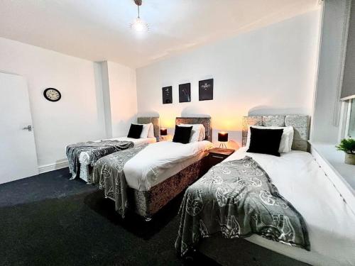 Cette chambre comprend deux lits et une horloge murale. dans l'établissement Modern Central 5 Bed Apartment, à Liverpool