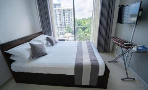 a bedroom with a bed with a large window at Quest Colombo Residencies in Talawatugoda