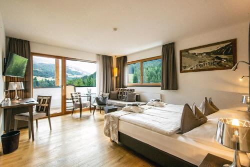 Hotel Ciasa Soleil في لا فيلا: غرفة نوم بسرير كبير وغرفة معيشة