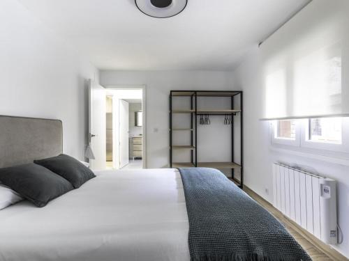 a white bedroom with a large white bed and windows at Munoa By Kabia Gestion in Barakaldo