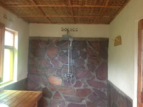 a shower in a room with a stone wall at Rushaga Gorilla Lodge in Bugambira