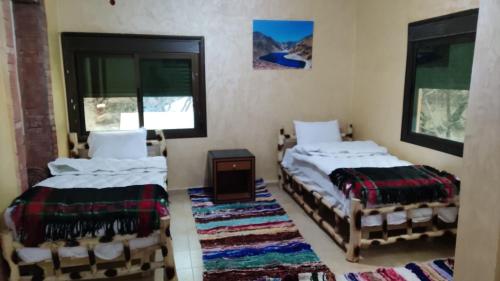 two beds in a room with two windows at auberge gite de jeunesse les Cascades in Setti Fatma