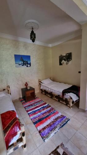 a living room with two beds and a rug at auberge gite de jeunesse les Cascades in Setti Fatma