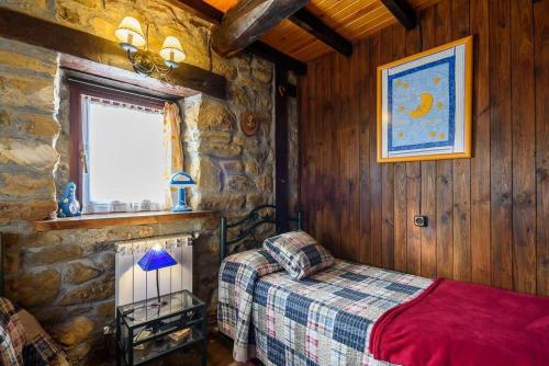 a bedroom with a bed and a stone wall at La Casa Rectoral de El Tozu in Caso