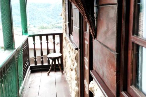 a balcony with a chair and a window at La Casa Rectoral de El Tozu in Caso