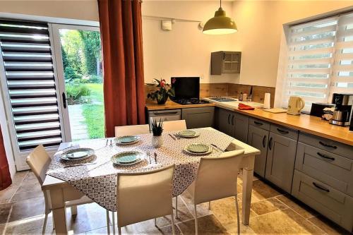 una cucina con tavolo, alcune sedie e tavolo e una cucina con di T-2 ouest 47m2 la maison au bord du Canal du Midi a Sainte-Colombe-en-Bruilhois