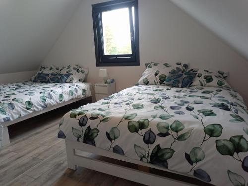 a bedroom with a bed with a comforter and a window at Domek letniskowy na Kaszubach, Borowy Młyn, jezioro Gwiazda in Borowy Młyn