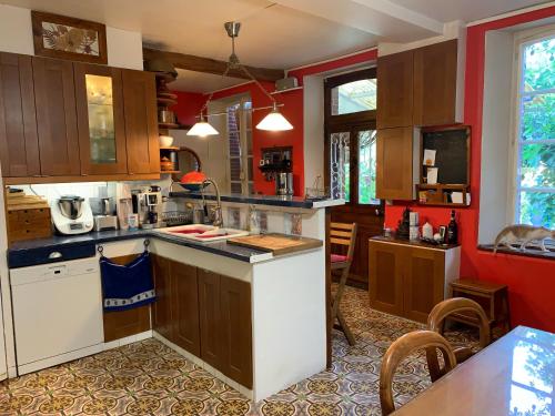 - une cuisine avec des murs rouges et des placards en bois dans l'établissement Chambres nature chez le particulier, à Courgenay