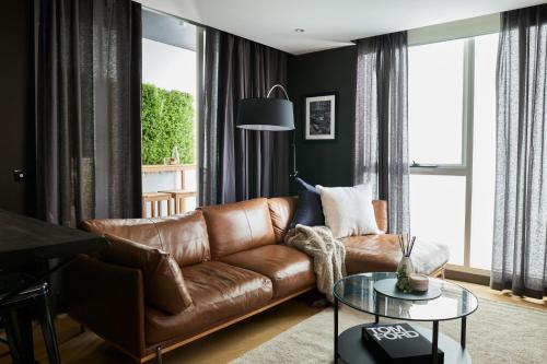 a living room with a brown leather couch at The Yorkshire Apartments Collingwood in Melbourne