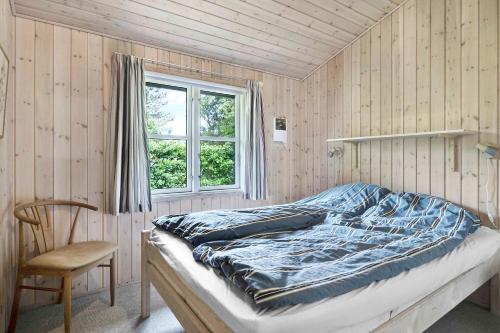 ein Schlafzimmer mit einem Bett, einem Stuhl und einem Fenster in der Unterkunft Cozy Cottage In A Quiet Area Close To The Beach in Dannemare