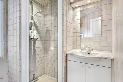 ein weiß gefliestes Bad mit einem Waschbecken und einer Dusche in der Unterkunft Cozy Cottage In A Quiet Area Close To The Beach in Dannemare