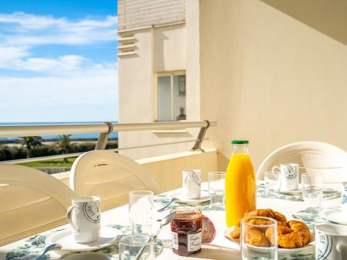 - une table avec de la nourriture et une bouteille de jus d'orange dans l'établissement Apartment Les Rivages de Rochelongue-2 by Interhome, au Cap d'Agde