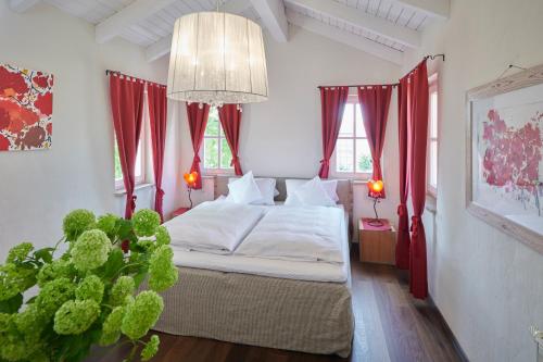 a bedroom with a bed with red curtains and a chandelier at Hotel Der Grischäfer in Bad Emstal