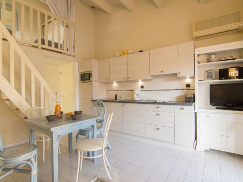 cocina con armarios blancos, mesa y sillas en Holiday Home Les Cristallines-2 by Interhome, en Cap d'Agde