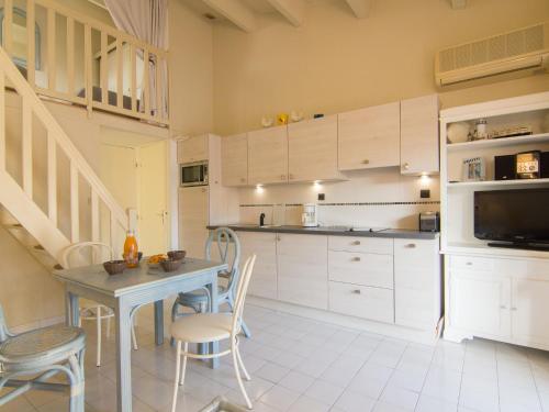 une cuisine avec des armoires blanches et une table et des chaises dans l'établissement Holiday Home Les Cristallines-2 by Interhome, au Cap d'Agde