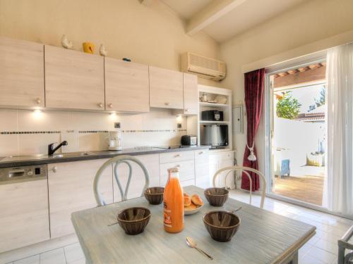 une cuisine avec une table, des chaises et une bouteille d'orange. dans l'établissement Holiday Home Les Cristallines-2 by Interhome, au Cap d'Agde