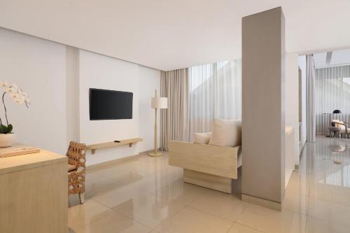 a white living room with a tv and a couch at COMO Uma Canggu in Canggu