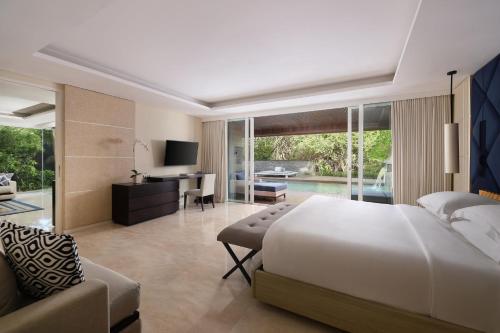 a bedroom with a bed and a desk and a couch at COMO Uma Canggu in Canggu