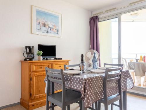 une salle à manger avec une table et des chaises et une télévision dans l'établissement Apartment Le Beach-1 by Interhome, à Canet
