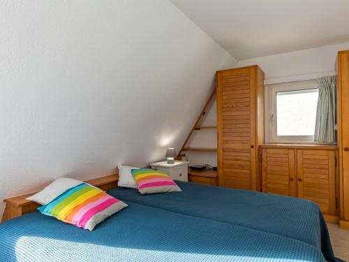 a bedroom with a blue bed with rainbow pillows at Holiday Home Tal Ar Mor - PLC213 by Interhome in Plounévez-Lochrist