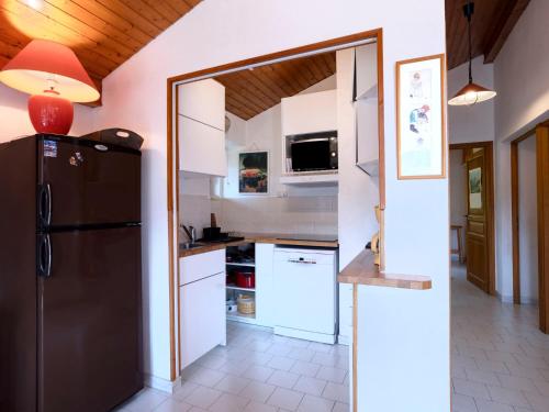 a kitchen with a black refrigerator and white cabinets at Apartment le Martagon-1 by Interhome in Saint-Gervais-les-Bains