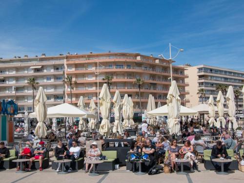 un groupe de personnes assises sous les chaises devant un bâtiment dans l'établissement Apartment Le régent-1 by Interhome, à Canet