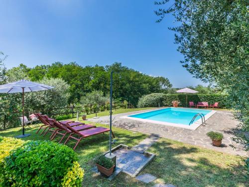 a swimming pool in a yard with chairs and an umbrella at Holiday Home Podere Cerbaia - SMR100 by Interhome in Santa Maria a Monte