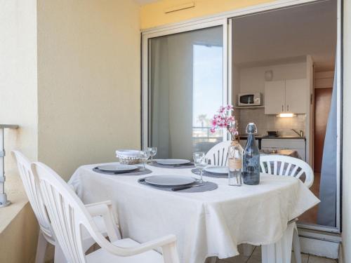 une table à manger avec des chaises blanches et un chiffon de table blanc dans l'établissement Apartment Le Beach-14 by Interhome, à Canet