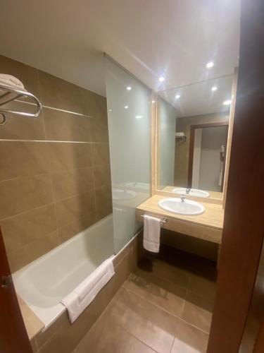 a bathroom with a tub and a sink and a mirror at Cityexpress Hotel San Fernando - Carcaixent 