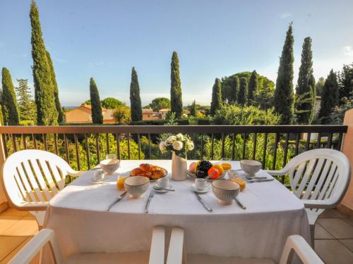 une table blanche avec de la nourriture sur un balcon arboré dans l'établissement Apartment les Oiseaux-1 by Interhome, à Cavalaire-sur-Mer