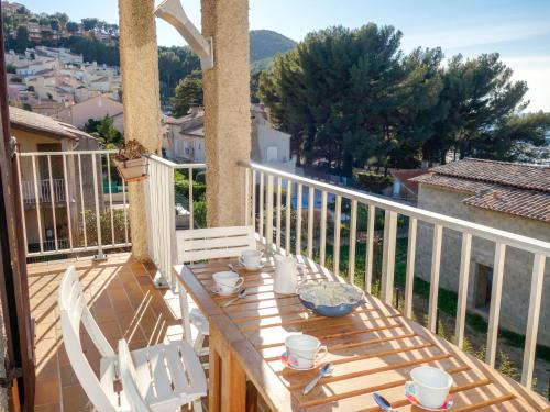 drewniany stół z białymi krzesłami na balkonie w obiekcie Apartment Les Aigues Marines-29 by Interhome w mieście La Madrague