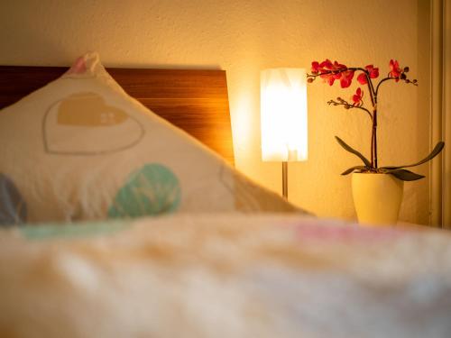 a flower in a vase on a bed with a lamp at Apartment Al-Khalid by Interhome in Dittishausen