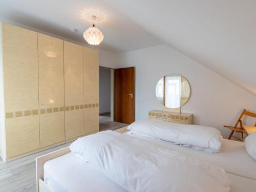 a white bedroom with two beds and a mirror at Apartment Hochfirst-2 by Interhome in Dittishausen