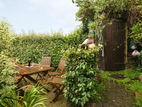 un jardin avec une table, des chaises et une haie verte dans l'établissement Holiday Home Ti Maen by Interhome, à Kernalléguen