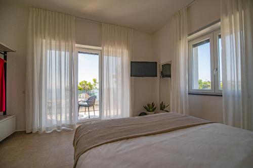 a bedroom with a bed and windows with a balcony at CALLIA ROOMS PROCIDA in Procida