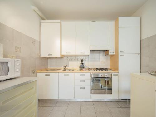 une cuisine blanche avec des armoires blanches et un micro-ondes dans l'établissement Apartment Villaggio 5 Terre-4 by Interhome, à Soviore