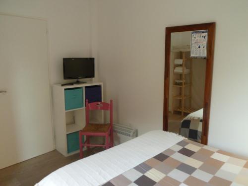 Schlafzimmer mit einem Bett, einem TV und einem Stuhl in der Unterkunft Hotel du Cap in Cap-Ferret