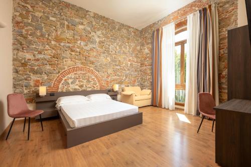 sypialnia z ceglaną ścianą oraz łóżkiem i krzesłami w obiekcie Hotel Villa Betania we Florencji