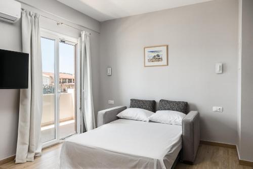 a bedroom with a bed and a large window at solarisuites in Mantoúkion