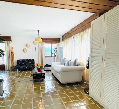 un soggiorno con divano bianco su pavimento piastrellato di Chalet Familial Capricorne a Vercorin