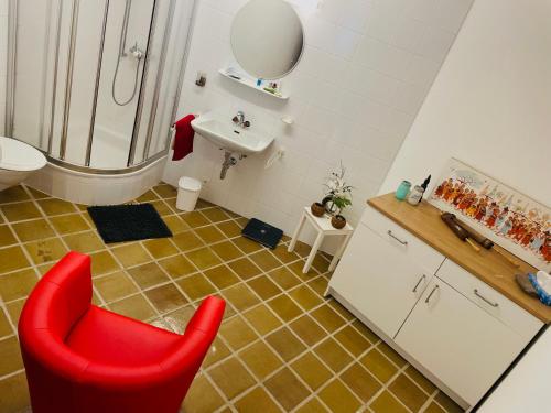 a bathroom with a red chair in front of a shower at Chalet Familial Capricorne in Vercorin