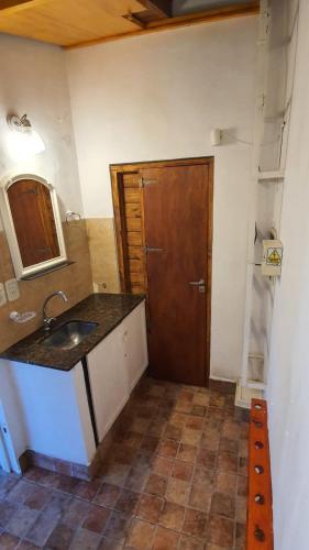 a bathroom with a sink and a wooden door at Casa Quinta La Gualeya in Gualeguay