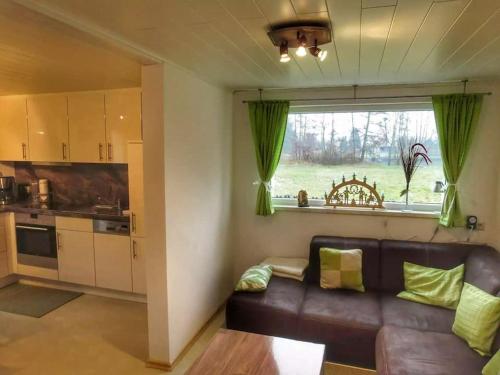 a living room with a leather couch and a kitchen at Spree am See - Dein Ferienhaus in Markische Heide