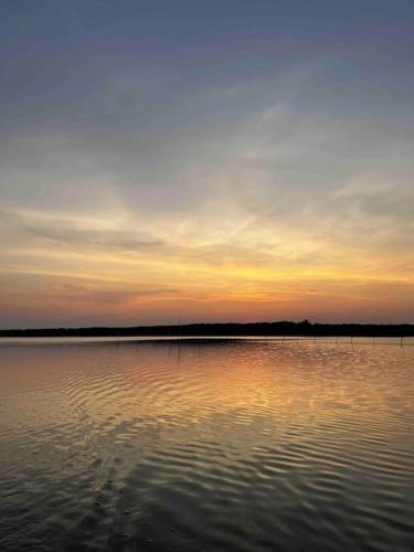 a large body of water with a sunset in the background at Spree am See - Dein Ferienhaus in Markische Heide