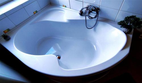 bañera blanca con grifo en el baño en Imádni Való Sarokkádas Apartman Salgótarján belvárosában, en Salgótarján