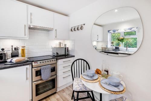 cocina blanca con mesa y espejo en Modern 1 bed-Nr Warner Bros-Parking-Garden en Watford