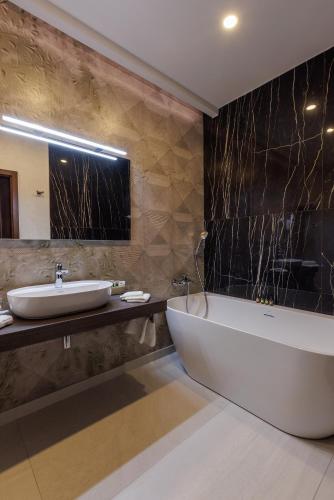 a bathroom with a white tub and a sink at Darovanský Dvůr - Wellness & Golf Hotel in Břasy