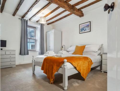 um quarto com uma cama branca com um cobertor laranja em Characterful 3 Bedroom Cottage em Aberystwyth