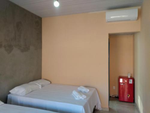 a room with two beds and a red refrigerator at Pousada Pérola do Rio in Barreirinhas